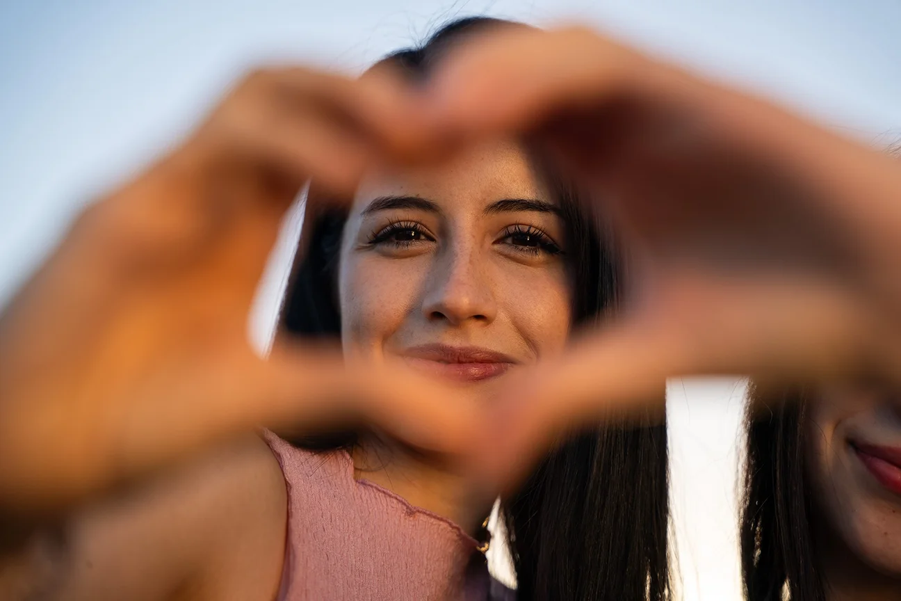Eine Frau macht mit ihren Händen eine schöne Herzform, um Liebe auszudrücken
